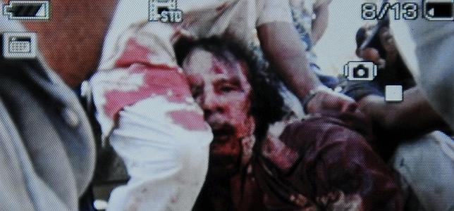 Imagen tomada con un móvil de cómo Gadafi es trasladado tras el ataque