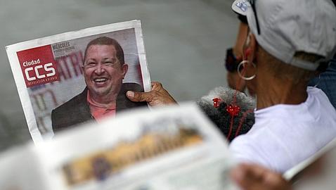 Una mujer lee un periódico con la imagen de Chávez