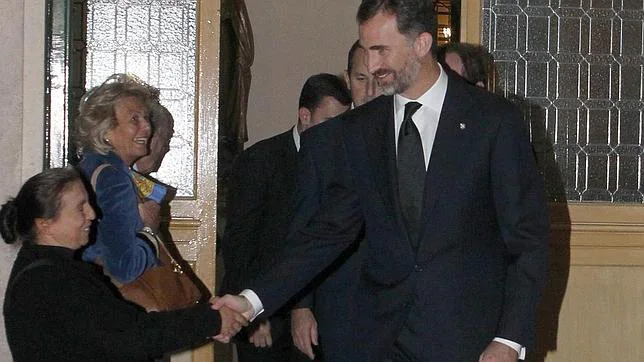 El Príncipe Felipe, en un funeral, le da la mano a una mujer que pedía limosna