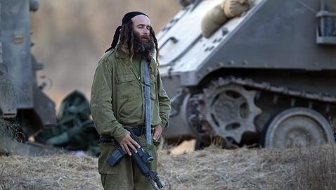 Un reservista israelí reza junto a un tanque