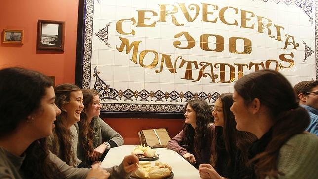 Varios jóvenes conversan en un «100 Montaditos» de Sevilla