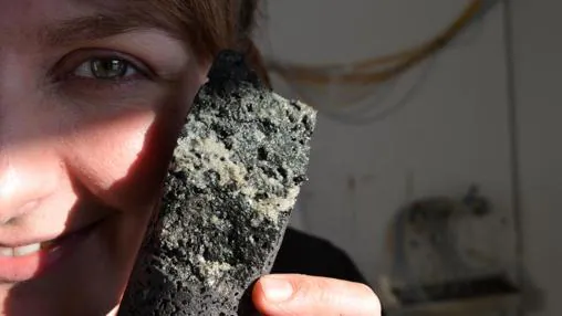La investigadora Sandra Snaebjornsdottir sostiene un fragmento de roca en el que se observan carbonatos solidificados, quizás gracias al bombeo llevado a cabo