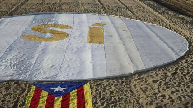 Imagen de una estelada acompañada de un «sí» a la independencia en la playa de Masnou