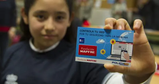 Una alulmna del colegio Sagrado Corazón de Jesús muestra la tarjeta de la Policía y Mapfre para tapar la webcam