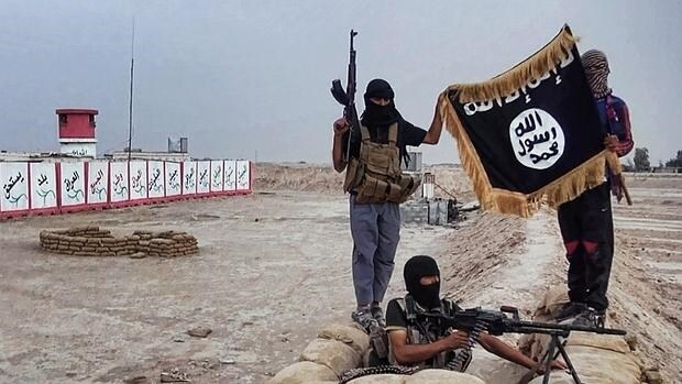 Combatientes de Daesh muestran una bandera de la organización terrorista
