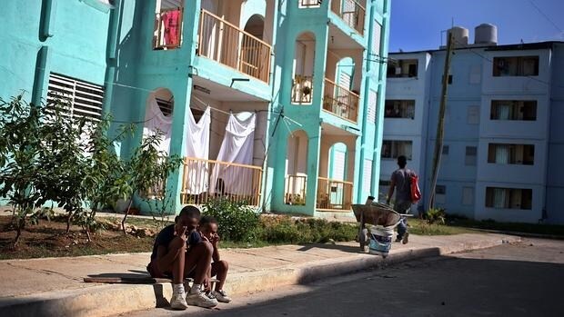 Unos niños posan junto a unas viviendas para personas sin recursos en Marianao (La Habana)