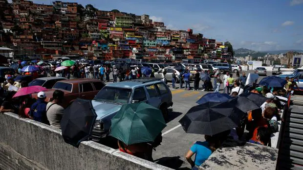 Varios venezolanos hacen cola para entrar en un supermercado de Caracas