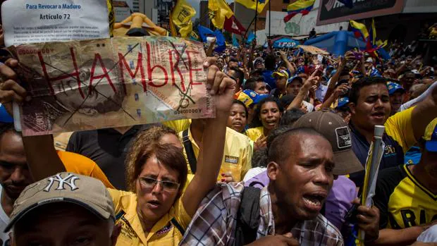 Una manifestante sostiene un letrero con la palabra «Hambre» en una protesta contra el Gobierno venezolano
