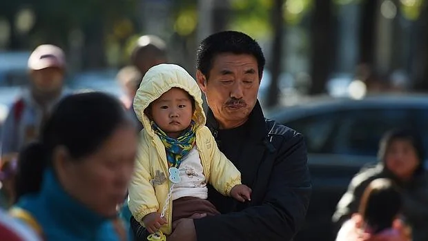 Uh hombre lleva a su hijo en brazos cerca de un hospital de Beijing, el 30 de octubre de este año