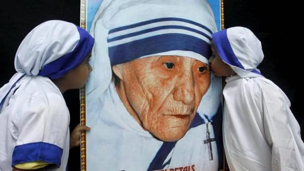 Dos niñas vestidas como Misionerasde la Caridad besna un retrato de la Madre Teresa de Calcuta