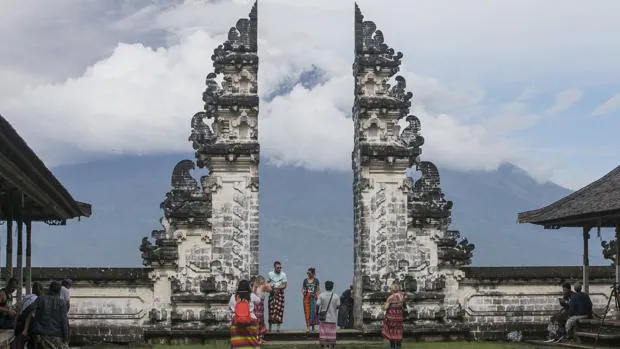 Turistas toman fotos del volcán Monte Agung que arroja ceniza volcánica caliente, visto desde el templo de Lempuyang