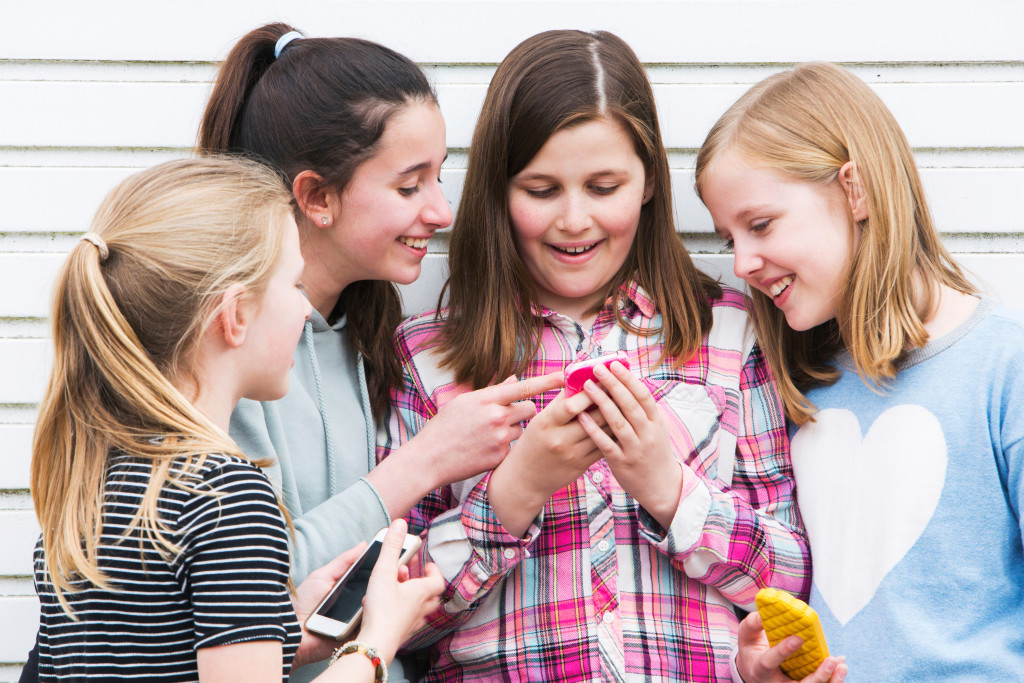 Group Of Young Girls Outdoors Looking At Message On Mobile Phone