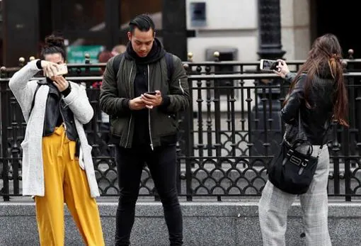 Unos jóvenes miran su teléfono móvil. Internet está cambiando el modo de buscar pareja, según expertos