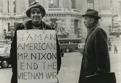 La madre del jugador de ajedrez Bobby Fischer, en frente de la opera de París, con un cartel pidiendo a Richard Nixon el fin de la Guerra de Vietnam (1973)