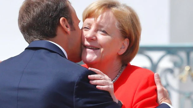 El presidente de Francia, Emmanuel Macron, besa a la canciller alemana, Angela Merkel