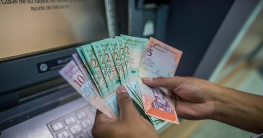 Una persona cuenta dinero del nuevo cono monetario retirado de un cajero automático