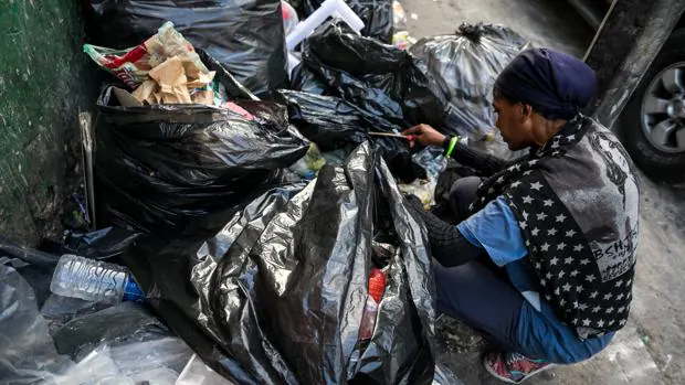 Una mujer mientras hurga en la basura en busca de comida en una calle de Caracas