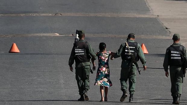 Soldados venezolanos llevan a una mujer de los brazos en la frontera con Brasil
